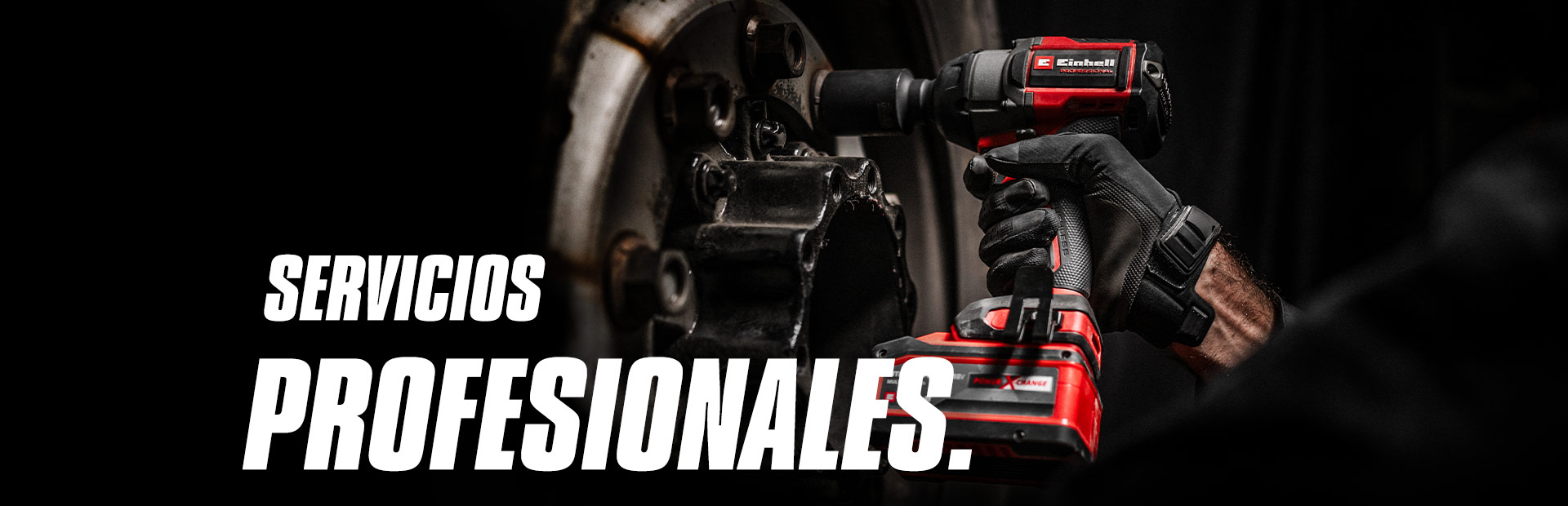 Primer plano de un atornillador de impacto inalámbrico rojo en uso sobre una rueda, con el texto "Servicios Profesionales."