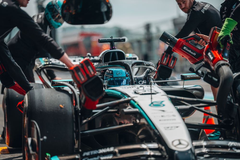 Un auto del equipo Mercedes-AMG PETRONAS Formula One durante una parada en boxes. Los miembros del equipo usan sopladoras inalámbricas Einhell para enfriar los componentes del vehículo. El equipo trabaja concentrado y con precisión.