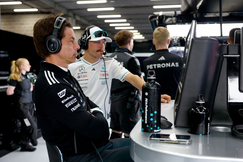 Toto Wolff y Valtteri Bottas, del equipo Mercedes-AMG PETRONAS Formula One Team, están en el puesto de trabajo del equipo dentro del garaje. Se concentran en la estrategia de carrera, observan los monitores y se comunican por auriculares.