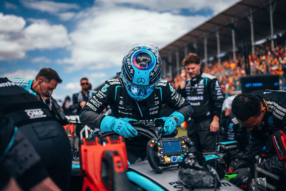 Mecánicos de Fórmula 1 trabajando en un coche de carreras en la calle de boxes.