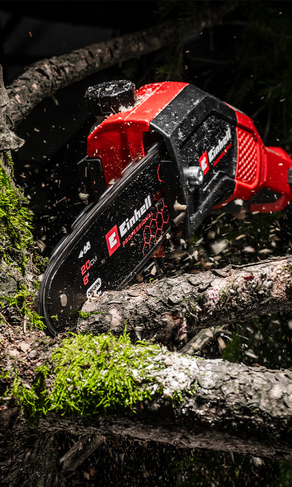 Motosierra Einhell cortando una rama, con aserrín volando en el aire.