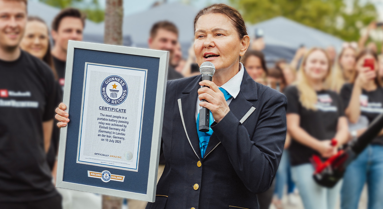 Una mujer con atuendo oficial de Guinness sostiene un certificado por el récord mundial de posta de baterías de Einhell.