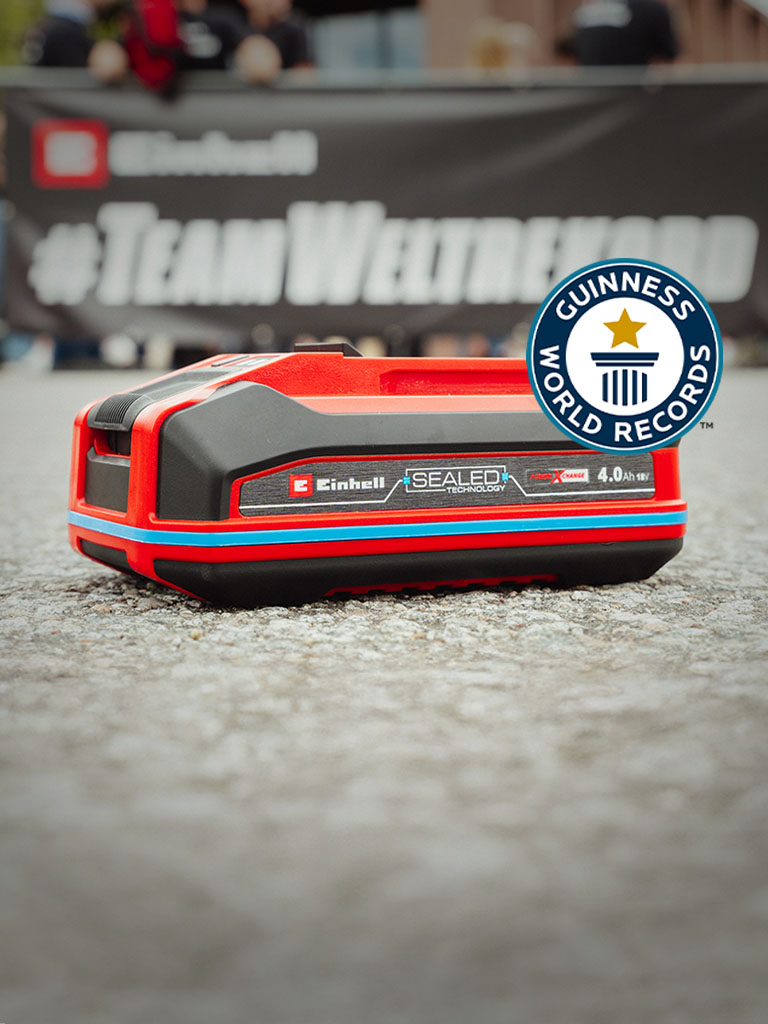 Einhell SEALED battery Power X-Change 4.0 Ah lies on asphalt, with the Guinness World Records logo on the right.