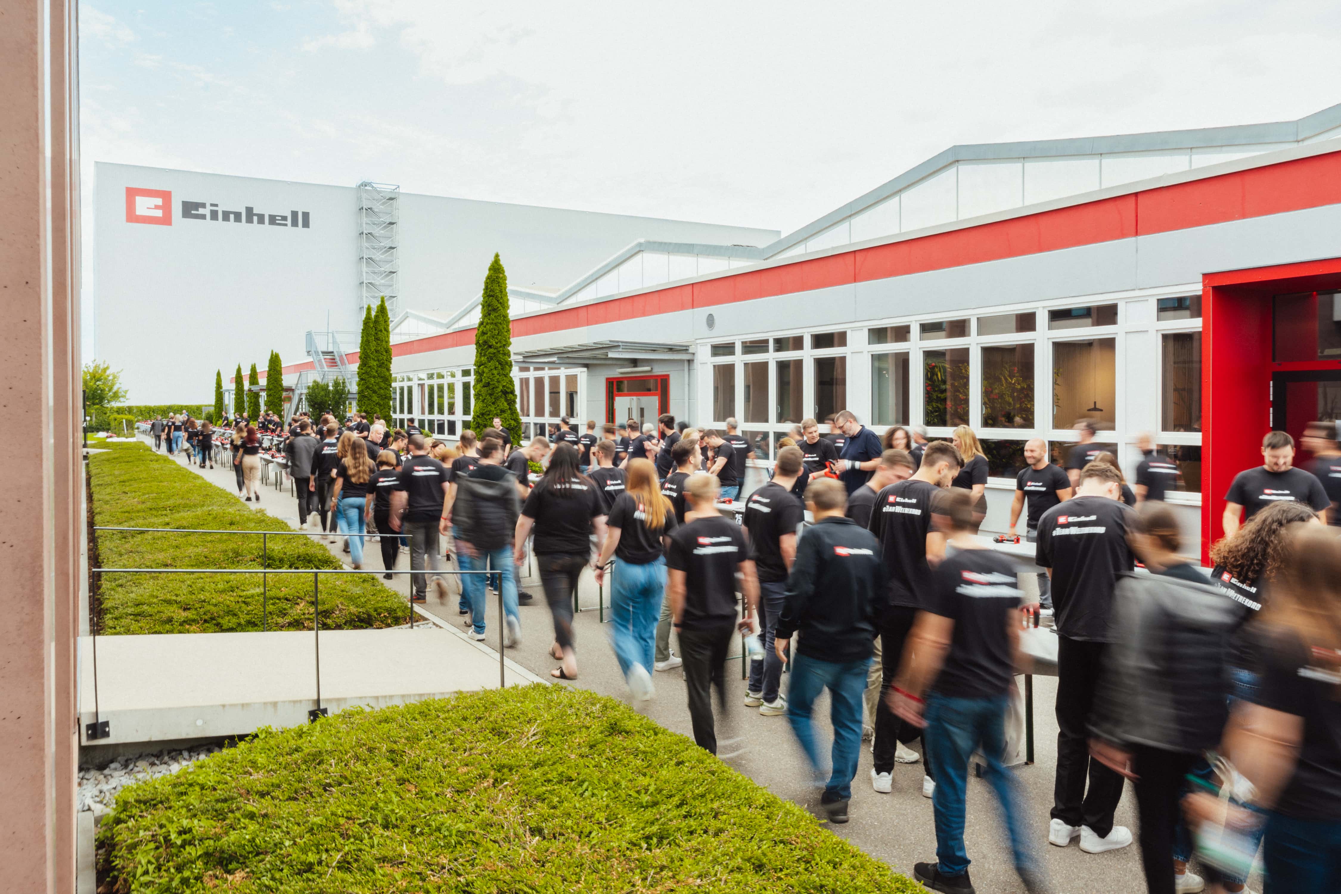 Human chain in motion during a battery relay with Einhell batteries in front of the company building.