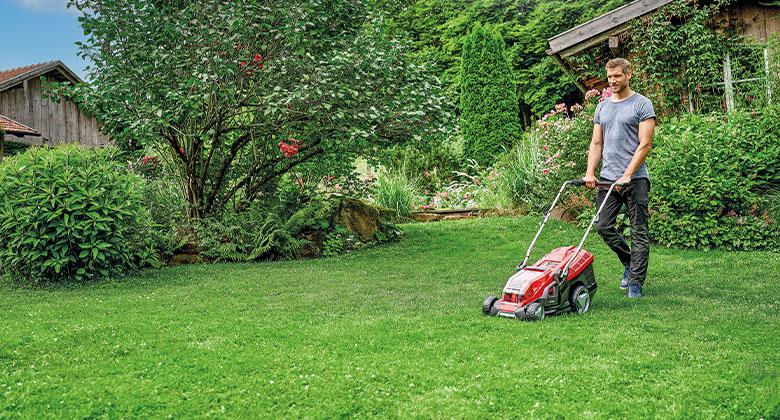 A man mowing a very large lawn with a 36 V battery lawnmower.