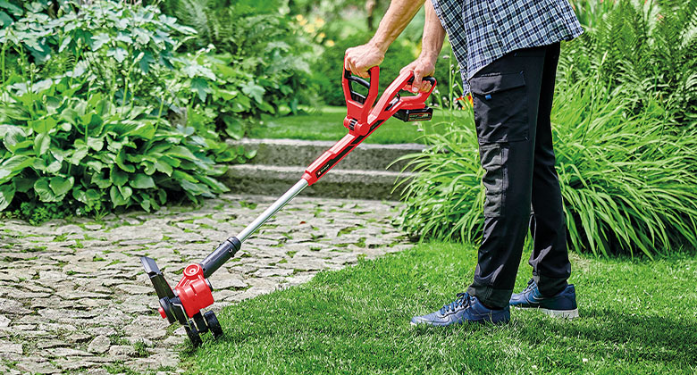 a man is using the edging function of the grass trimmer