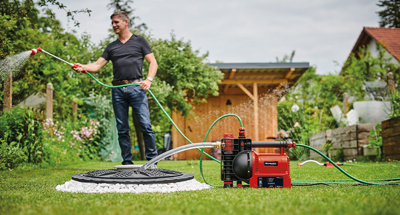 A man watering plants. The water needed is pumped from a cistern by a garden pump.